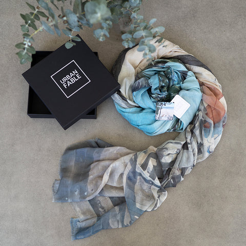 A black gift box and scrolled up cotton linen scarf featuring a design of Little Cove in Noosa.