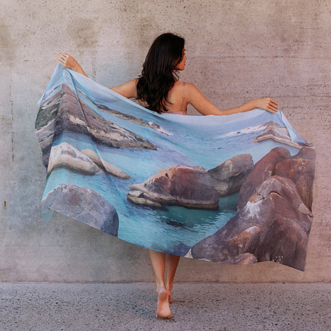 A girl standing holding out a cotton scarf stretched out flat featuring Elephant rocks in Denmark Western Australia
